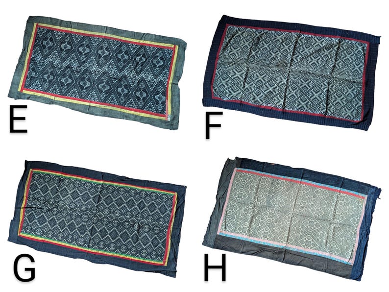 May include: Rectangular textile with a geometric pattern in shades of blue, with a red and yellow border. The textile is displayed on a white background. The textile is labelled with the letter "E".