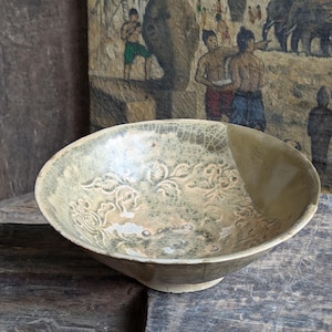 May include: A green and white ceramic bowl with a floral design. The bowl has a crackled glaze and is slightly chipped.