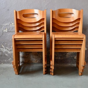 May include: Two wooden chairs with a unique, layered design. The chairs are made of light brown wood and have a curved back and seat.