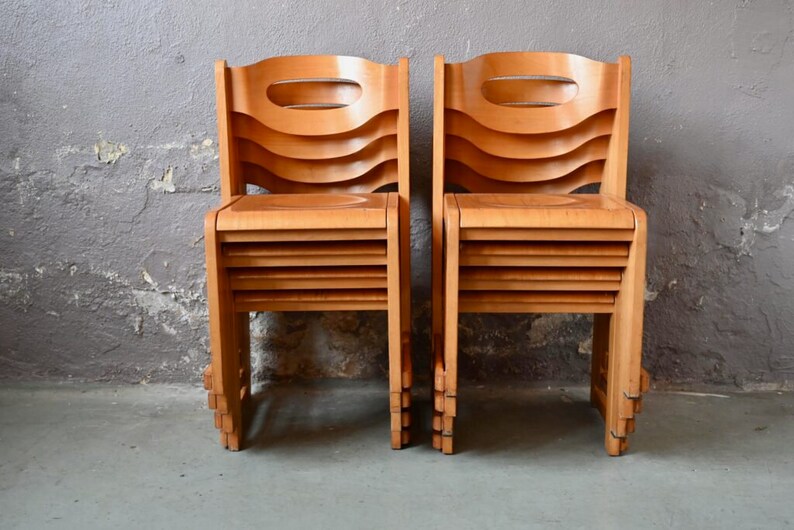 May include: Two wooden chairs with a unique, layered design. The chairs are made of light brown wood and have a curved back and seat.