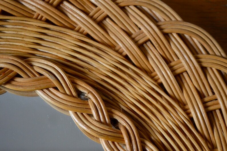 May include: Close-up of a woven wicker frame, showing the intricate details of the natural material. The frame is made of light brown, tightly woven strands of wicker, creating a textured and organic pattern.