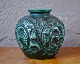 Op de afbeelding: Een groene keramische vaas met een ingewikkeld reliëf van bladeren en spiralen.