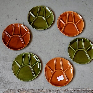 Op de afbeelding: Zes verdeelde keramische borden in groen en oranje. De borden hebben elk vijf secties.