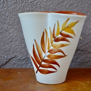 May include: White ceramic vase with a brown and yellow fern leaf design.