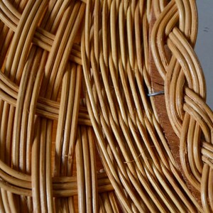 May include: Close-up of a woven wicker frame with a natural brown color. The frame is made of thin, tightly woven strips of wicker, creating a detailed and intricate pattern.