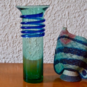Peut inclure: Un vase en verre vert avec un motif en spirale bleu et une figurine de poisson en céramique bleue et blanche.