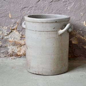 Op de afbeelding: Een grote, witte keramische pot met twee handvatten. De pot heeft een licht getextureerd oppervlak en is in goede staat.