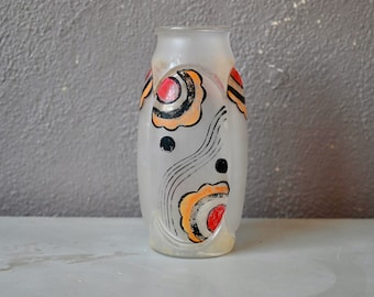 Op de afbeelding: Een frosted glazen vaas met een abstract ontwerp met zwarte, oranje, rode en witte details. De vaas heeft een ronde, cilindrische vorm.