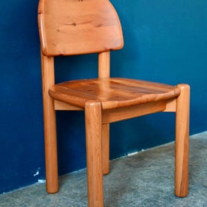 May include: A solid wood chair with a rounded back and four legs. The chair is made of natural wood with a light brown finish.