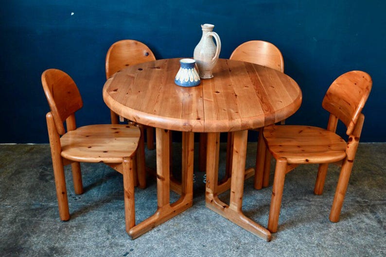 May include: A round wooden table with four chairs. The table and chairs are made of light brown wood. There is a blue and white ceramic jug and a blue and white ceramic cup on the table.