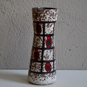 Könnte beinhalten: Eine weiße Keramikvase mit einem geometrischen Muster aus schwarzen Quadraten und roten Kreisen. Die Vase hat eine gesprenkelte Glasur und eine leicht ausgestellte Öffnung.
