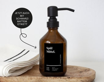 May include: A brown glass bottle with a black pump dispenser and a black label that reads "Spül Mittel." The label also includes the text "Premium Qualität" and details about the product, including size, ingredients, and design.