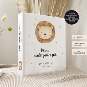 Könnte beinhalten: Weißer Ordner mit einer Löwenillustration und dem Text "Meine Kindergartenzeit" und "LUIS MUSTER 2025-2028". Der Ordner hat goldene Punkte und eine Löwenillustration auf dem Rücken. Der Ordner hat A4-Format und eine Rückenbreite von 5/7,5 cm.