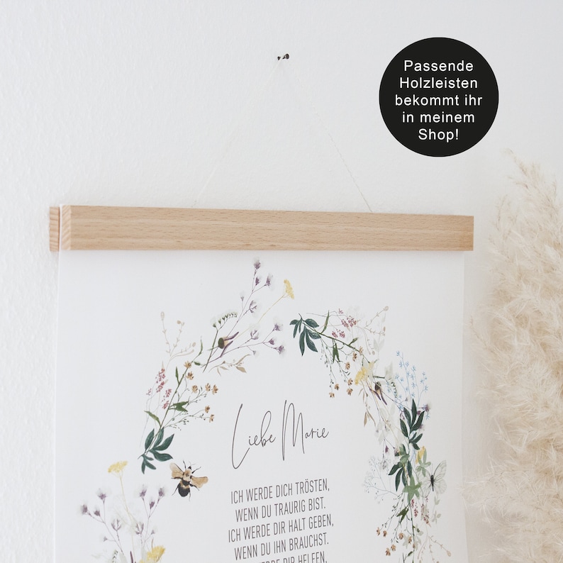 May include: A white poster with a floral wreath and the text "Liebe Marie" in black script. The text below the wreath reads "Ich werde dich tr&ouml;sten, wenn du traurig bist. Ich werde dir Halt geben, wenn du ihn brauchst. Wenn du dir helfen."