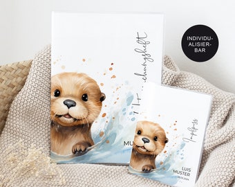 Op de afbeelding: Twee aquarel illustraties van otters in een blauwe golf. De grotere illustratie is op een witte achtergrond met de tekst "11+...schungsheft" en "MU". De kleinere illustratie is op een witte achtergrond met de tekst "Impfpass" en "LUIS MUSTER 28.03.2004".