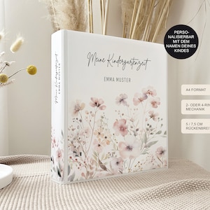 Könnte beinhalten: Ein weißer A4-Ordner mit einem floralen Aquarell-Druck in Rosa- und Beigetönen. Auf dem Einband steht der Text "Meine Kindergartenzeit" und "EMMA MUSTER". Der Buchrücken zeigt ebenfalls den Text "Meine Kindergartenzeit" und "EMMA MUSTER".