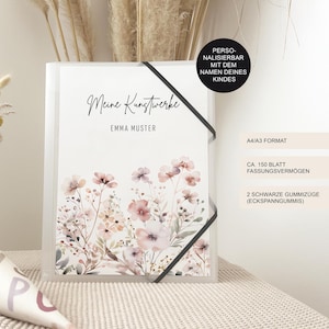 Könnte beinhalten: Ein transparenter Kunststoffordner mit einem Blumendesign mit rosa und pfirsichfarbenen Blüten. Der Ordner hat einen schwarzen Gummibandverschluss und den Text "Meine Kunstwerke" und "EMMA MUSTER".