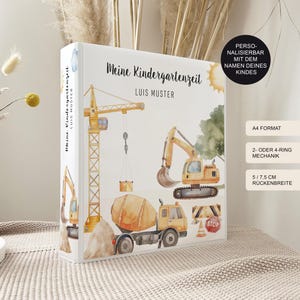 Könnte beinhalten: Ein weißer Ordner mit gelbem Bau-Motiv. Der Ordner zeigt einen gelben Kran, einen gelben Bagger und einen gelben Betonmischer. Der Text "Meine Kindergartenzeit" und "LUIS MUSTER" ist auf der Vorderseite des Ordners gedruckt. Der Ordner ist im A4-Format und hat einen 5 cm x 7,5 cm breiten Rücken.