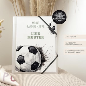 Könnte beinhalten: Ein transparenter Ordner mit einem Fußballmotiv. Der Ordner trägt den grünen Text "MEINE SAMMELMAPPE LUIS MUSTER". Er hat ein schwarzes Gummiband und den Text "PERSONALISIERBAR MIT DEM NAMEN DEINES KINDES".