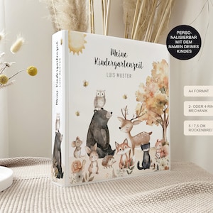 Könnte beinhalten: Ein weißer Ordner mit einer Waldtier-Illustration. Der Ordner ist personalisiert mit dem Text "Meine Kindergartenzeit" und "LUIS MUSTER". Der Ordner ist im A4-Format und hat einen 5,75 cm breiten Rücken.