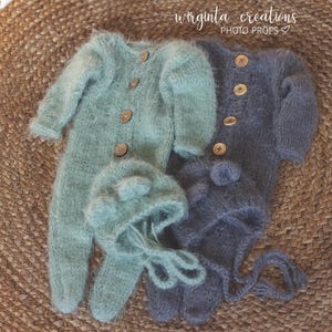 Op de afbeelding: Twee gebreide baby-outfits, een in lichtgroen en de andere in donkergrijs. Beide outfits hebben een pluche textuur en knoopsluitingen. De groene outfit bevat een bijpassende muts met berenoren. De tekst "wirginta creations PHOTO PROPS" is zichtbaar in de rechterbovenhoek van de afbeelding.
