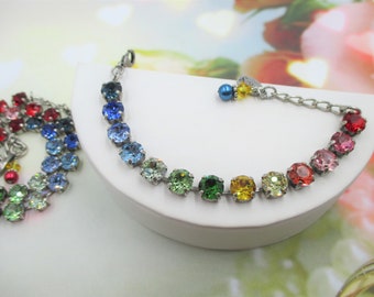 May include: A colourful bracelet with a silver chain and clasp. The bracelet features round gemstones in red, pink, orange, yellow, green, blue, and purple. A second bracelet is visible in the background.