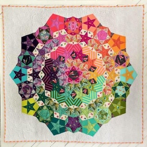 May include: A vibrant, handmade quilt with a starburst design. The quilt features a kaleidoscope of colors, including pink, orange, green, and purple, arranged in a geometric pattern. The quilt is bordered with a white fabric and a decorative orange stitch.