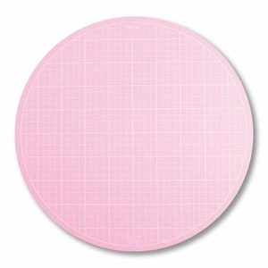 May include: Pink self-healing cutting mat with a grid pattern. The mat is round and measures approximately 12 inches in diameter.