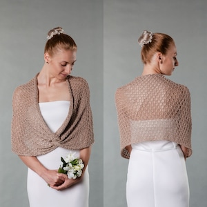 Könnte beinhalten: Ein hellbraunes gestricktes Tuch mit einem zarten Lochmuster. Das Tuch ist über die Schultern einer Person gelegt, die ein weißes Kleid trägt.