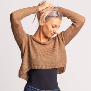 May include: A brown cropped sweater with a loose fit and a slightly cowl neck. The sweater is made of a soft, knitted fabric.