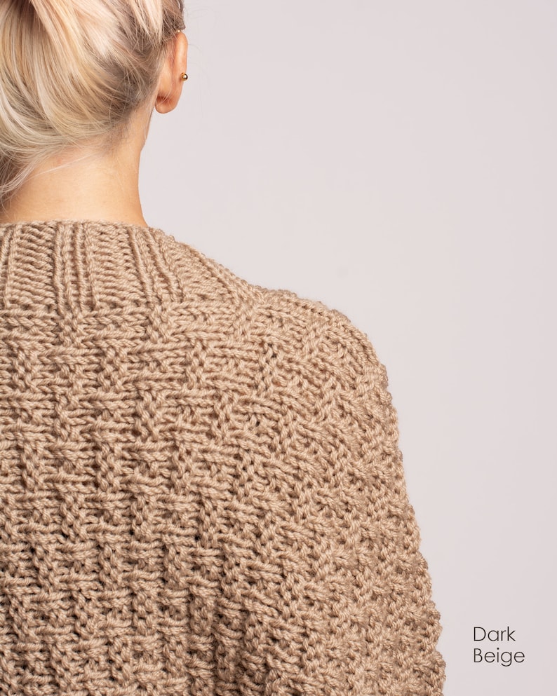 May include: A dark beige knitted jumper with a cable knit pattern.