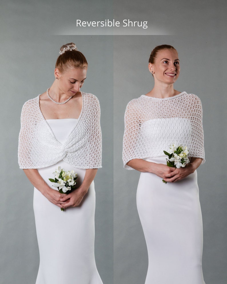 May include: White crocheted shrug with a delicate openwork pattern. The shrug is reversible, showing a different texture on each side. The model is wearing a white dress and holding a small bouquet of white flowers.