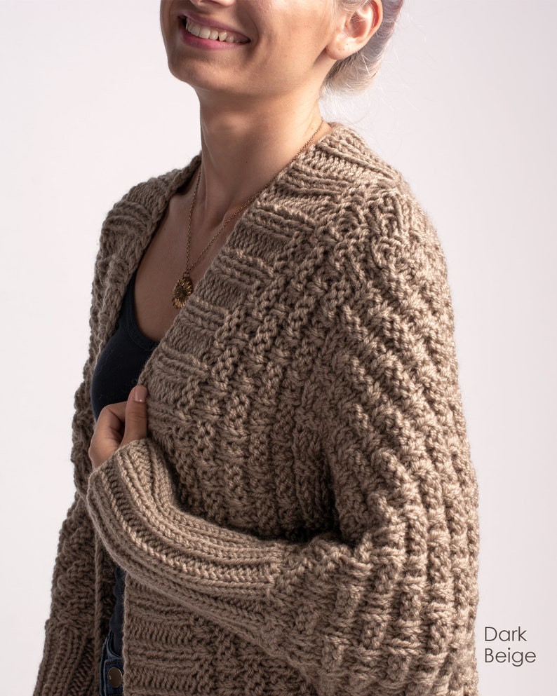 May include: A dark beige knitted cardigan with a cable knit pattern. The cardigan is open at the front and has long sleeves.