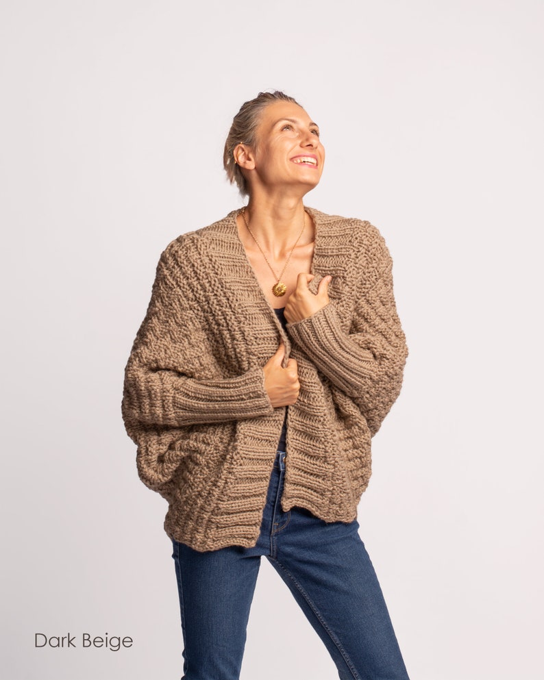 May include: A dark beige knitted cardigan with a relaxed fit and long sleeves. The cardigan is open at the front and has a V-neck.