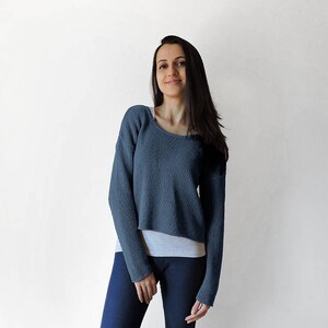 May include: A blue cropped sweater with long sleeves. The sweater is made of a soft, knit fabric.