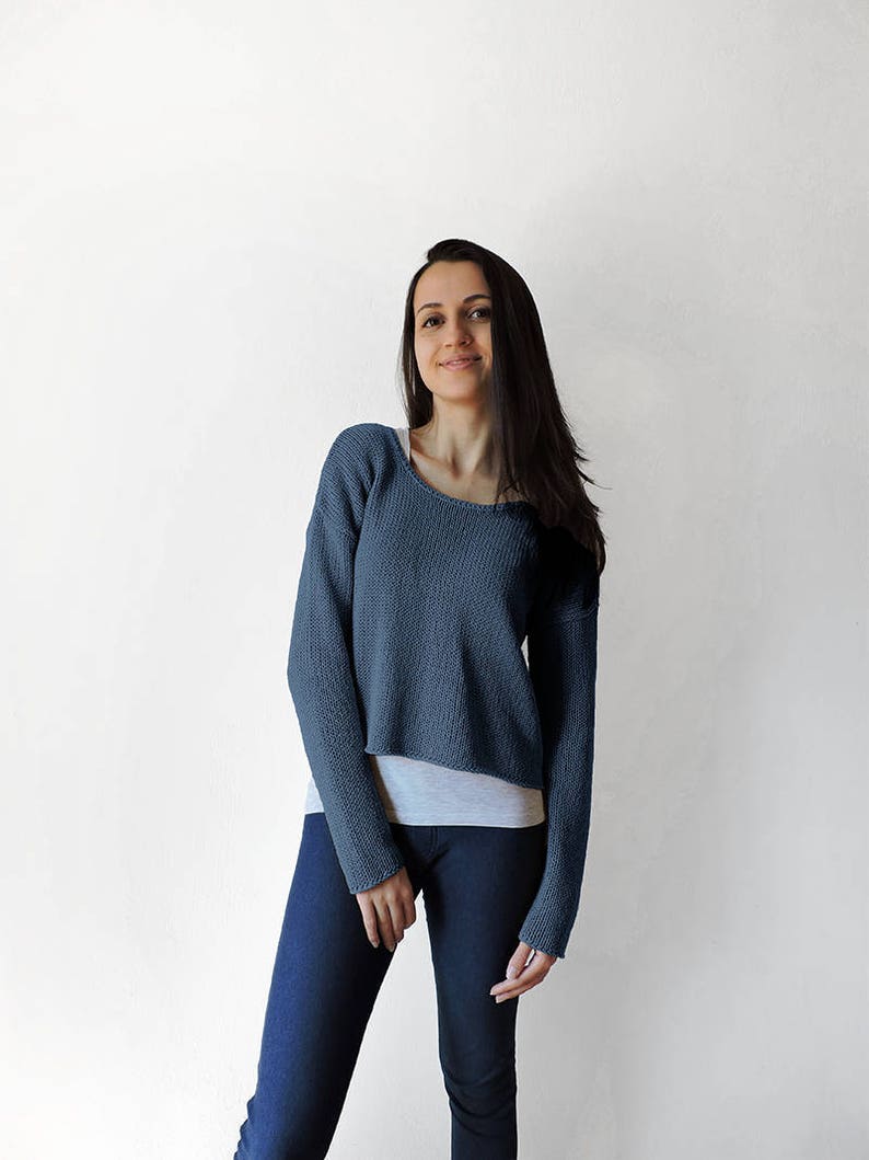 May include: A blue cropped sweater with long sleeves. The sweater is made of a soft, knit fabric.