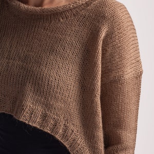 May include: A brown knitted sweater with a cropped hem and long sleeves.