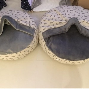 May include: Two round pet beds with a grey fleece lining and a beige outer fabric with a dachshund print.