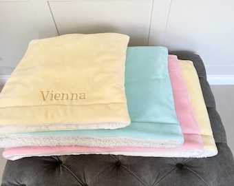 May include: A stack of four plush blankets in yellow, light blue, pink, and white. The top blanket has the name "Vienna" embroidered on it.