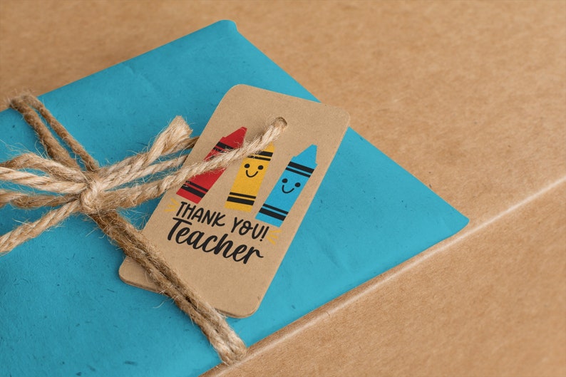 May include: A gift wrapped in blue paper, tied with twine, and a brown tag. The tag features three smiling crayon illustrations in red, yellow, and blue, with the text "THANK YOU! Teacher".