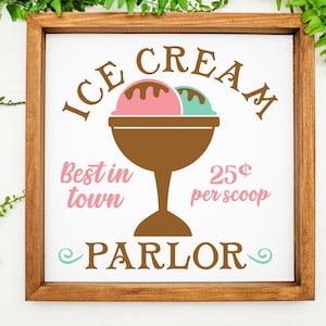 May include: A white sign with brown text that reads "ICE CREAM" in a curved arch above a brown ice cream dish with two scoops of ice cream, one pink and one green. The text "Best in town" is in pink below the ice cream dish and "25&cent; per scoop" is in pink to the right of the dish. The text "PARLOR" is in brown below the ice cream dish with a swirl design on either side.