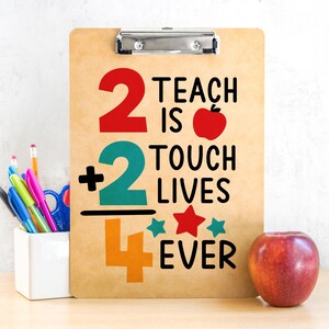 May include: A clipboard with the text "2 Teach is 2 Touch Lives Ever" in red, teal, and orange. An apple and a pencil holder with pens and pencils are next to the clipboard. The clipboard is brown.