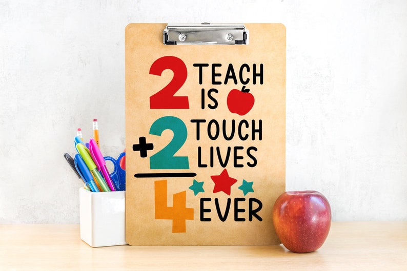 May include: A clipboard with the text "2 Teach is 2 Touch Lives Ever" in red, teal, and orange. An apple and a pencil holder with pens and pencils are next to the clipboard. The clipboard is brown.