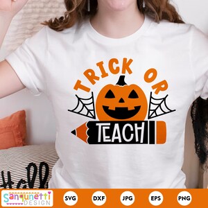 Pode incluir: Camiseta branca com o texto "Trick or Teach" em laranja e preto. Uma ab&oacute;bora preta e laranja com uma cara assustadora est&aacute; no centro do texto. Um l&aacute;pis preto e laranja com uma borracha vermelha est&aacute; abaixo do texto.