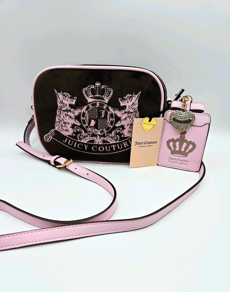 May include: A black crossbody bag with a pink strap and trim, featuring a pink crest design with the words "Juicy Couture." A matching pink cardholder and tag are also included.