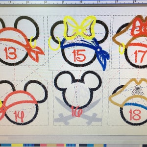 May include: A print featuring six Mickey Mouse head outlines, each with a unique design. Some are pirate-themed with bandanas and earrings, while others have bows and pirate hats. Numbers 13, 14, 15, 17, and 18 are visible.