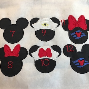 May include: Embroidered black Mickey Mouse head patches with red numbers and bows. Some have sailor hats and cruise ship logos. Numbers 7, 8, 9, 10, 11, and 12 are visible. These patches are likely for crafting or apparel.