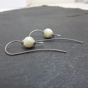 May include: A pair of silver earrings with white pearl-like beads.