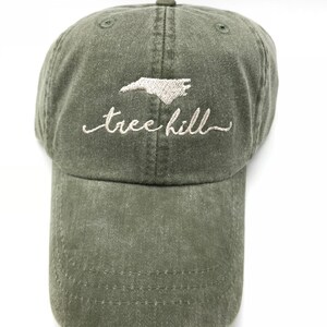 Pode incluir: Um bon&eacute; de beisebol verde com um contorno bordado do estado da Carolina do Norte e o texto "tree hill" em branco.