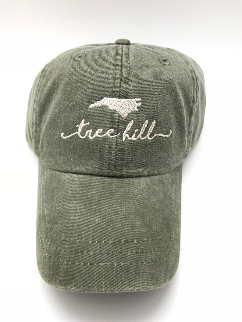 Pode incluir: Um bon&eacute; de beisebol verde com um contorno bordado do estado da Carolina do Norte e o texto "tree hill" em branco.